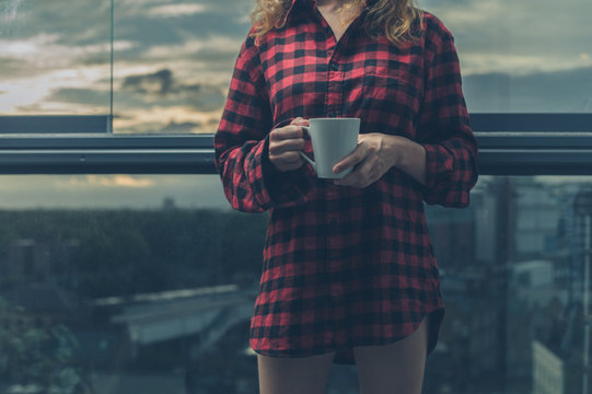 Woman drinking coffee on balcony at sunrise