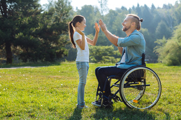 Young father with mobility impairment high-fiving daughter