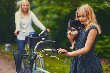 Blond girl on a bicycle holds a Spitz dog.