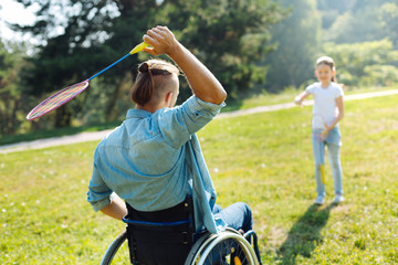 Mobility-impaired man passing shuttlecock to daughter
