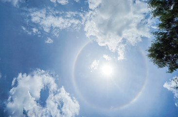 corona of the Sun in bright blue sky with white clouds