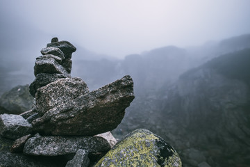 Human-made pile of stones - cairn as way marker in foggy mountain © Soloviova Liudmyla