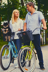 Obraz premium Blond woman and a man on a bicycle ride in a park.