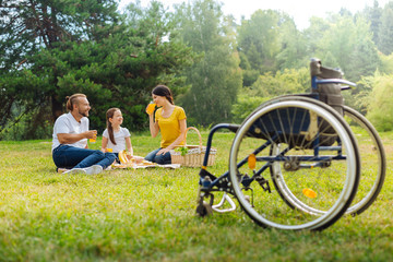 Family of a disabled man drinking juice in the meadow