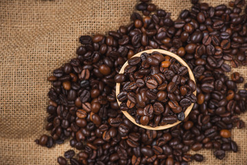 Wooden bowl with roasted coffee beans on rustic background.