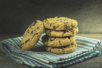 Stacked Traditional chocolate chip cookie on napkin on wooden table.