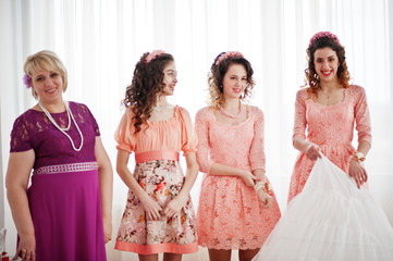 Naklejka premium Bridesmaids and mother looking at bride while she is dressing up.