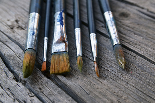Paint brushes on old wooden background.Set of artistic paintbrushes.Brushes for painting on a rustic table.Selective focus.