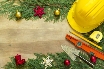 Protective helmet, mason tools  and Christmas decorations on wooden background