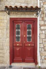 Fototapeta na wymiar Vintage red wooden door in village of Greece