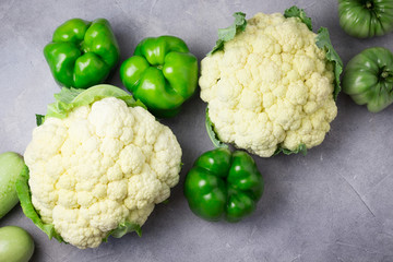 Variety of green vegetables on concrete, stone background. Cauliflower, leek, zucchini, squash, tomatoes, bell pepper on concrete backcround. Top view, copyspace.