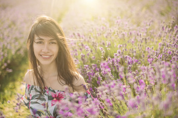 Happy smiling Spanish Colombian woman is among the flowers of blooming lavender.  Romantic mood photo