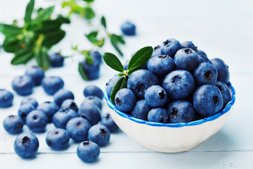 Blueberry or great bilberry in bowl on blue rustic background. Organic superfood and healthy nutrition.
