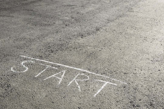 The inscription of crayons "Start" on the asphalt. The concept of the beginning of something