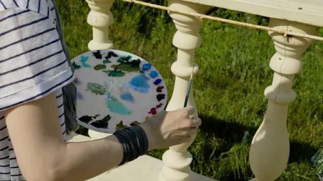 Landscape painter. A young female artist painting a natural scenery with oil paints. 4K