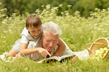 Grandfather and grandson reading book