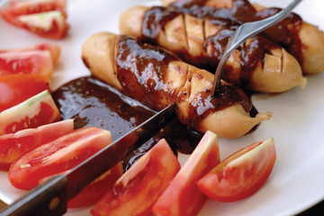 Smoked sausage with gravy sauce and tomato.