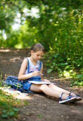 Naklejka premium Girl painter draws in a park sitting on the ground.