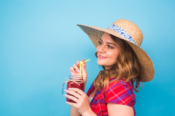 Sexy cute girl posing in studio, drinking fruit juice or cocktail on blue background and copy space