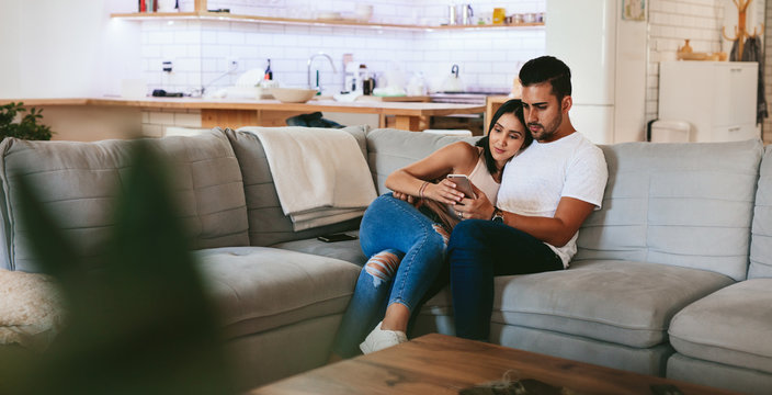 Couple relaxing on couch with smartphone