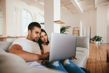 Loving young couple using laptop at home