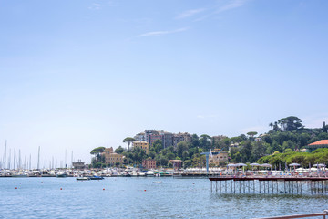 Fototapeta na wymiar Daylight view to mountains, blue sea, beach pier and city of Rapallo, Italy.