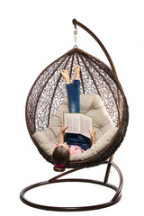 The girl rests in a hanging chair made of rattan.