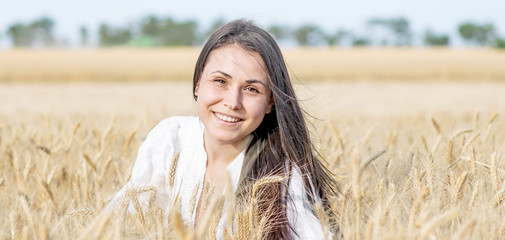 Portrait of a beautiful sexy woman smiling in wheat field at sunny summer day. Copy space left