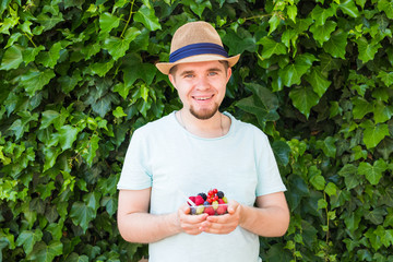 Concept of vegetarians, raw food and diets - Handsome man hold fruits and berries