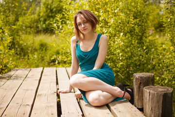 Young girl in blue dress sitting on wooden pierce