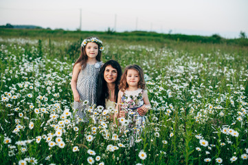 Mom with baby in daisy field at sunset. Toning