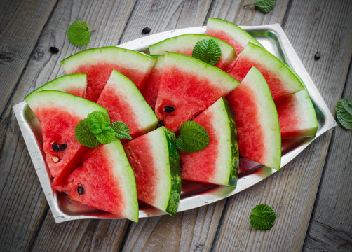 Fresh sliced watermelon in a metal bowl wooden background