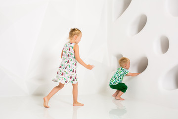 Brother and sister playing and smiling in a white studio