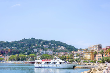 Fototapeta premium Beautiful view to city and mountains of Rapallo, Italy. Ship on blue water.