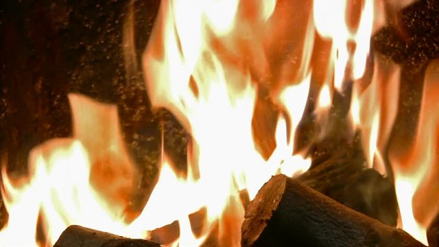 Bright dancing orange flames rising from a blazing domestic log fire.