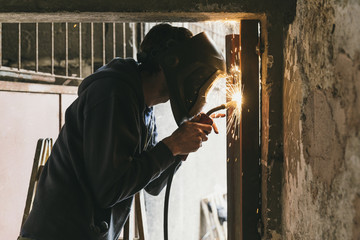 Blacksmith with welder mask welding a metal frame