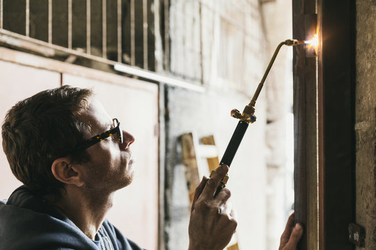 Blacksmith brazing door hinges at construction site