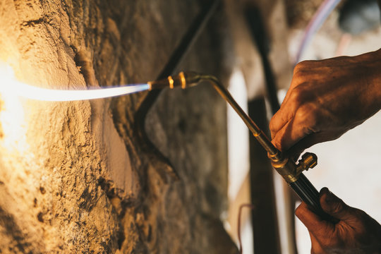 Hands operating a flaming brazing machine for welding