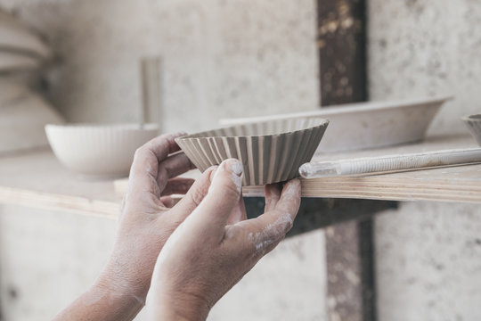 Hands of a ceramic artist placing a bowl on a shelf