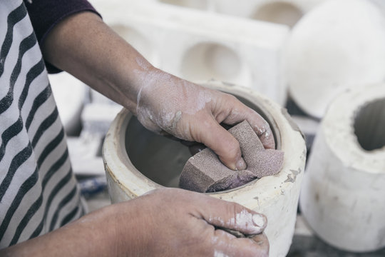 Hands of a ceramic artist working on a cast mould
