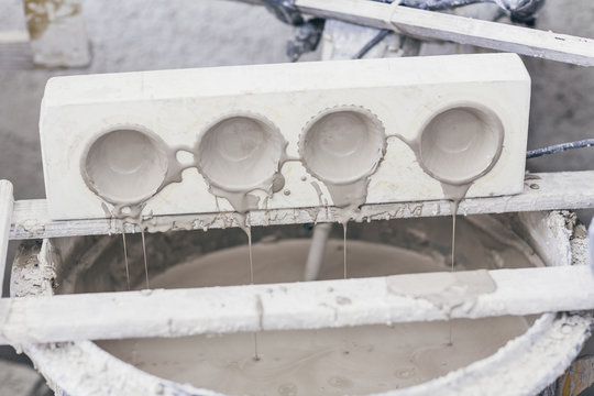 Ceramic clay moulds dripping over bucket of wet slip