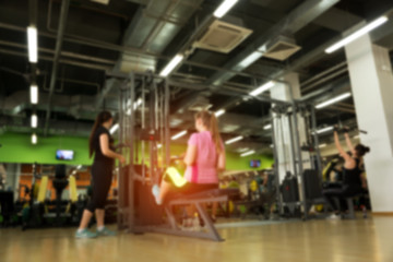 Fototapeta na wymiar Blurred picture of exercising females in gym