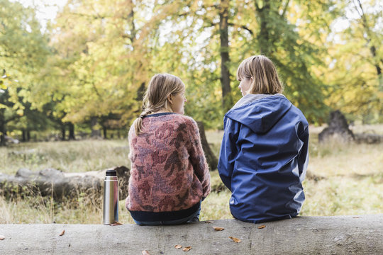 Two female friends sitting, chatting in the forest