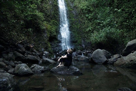 woman sitting in front of waterfall
