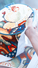Hands of a woman, cross-stitch, close-up