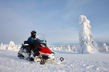 Man driving snowmobile in snowyfield in a sunny day. Lapland, Finland.