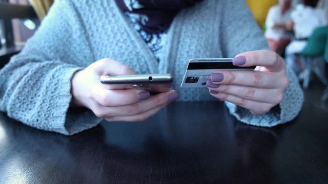 Young caucasian female hands buying goods from the internet on his smartphone with his credit card.