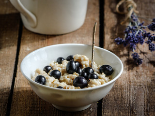Oatmeal porridge with berry black currant, a cup of hot drink and a small bouquet of lavender