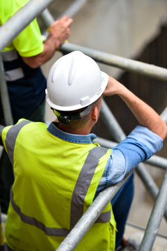 Workers inspecting construction works on a scaffold