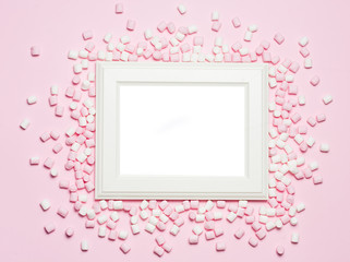 Pink and white Marshmallows and wooden frame with free space for text on pastel pink background. Top view, flat lay.